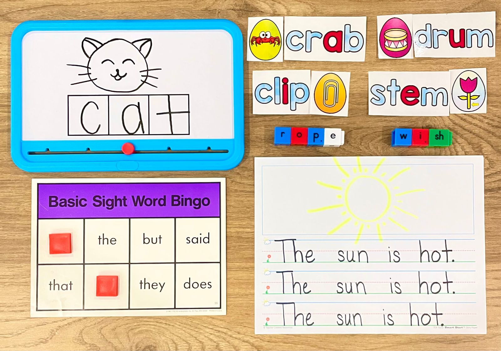 Early elementary reading materials: CVC word building on a whiteboard, picture-sound cards, sight word bingo, and handwriting practice